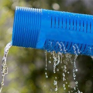 Blue threaded borehole casing pipe flowing with water